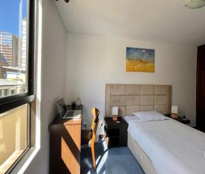 Un dormitorio con una cama y un escritorio y una ventana. en Apartamento completo -Acuario Suites, en La Paz