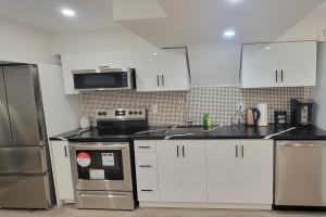 a kitchen with white cabinets and stainless steel appliances at Lake-Walk House in Hamilton