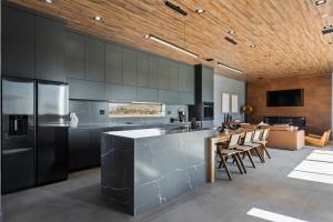 a kitchen with black cabinets and a bar with chairs at Black C House- Pool & Spa in Joshua Tree