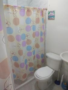 een badkamer met een toilet en een douchegordijn bij Hospedaje Villa Fati in Coveñas
