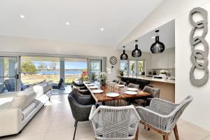 - une salle à manger et un salon avec une table et des chaises dans l'établissement Lake Palm Resort Luxury Retreat absolute Waterfront on 3 acres at Lake Macquarie., à Dora Creek