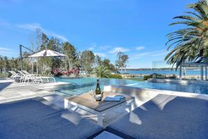 - une bouteille de vin assise sur une table à côté de la piscine dans l'établissement Lake Palm Resort Luxury Retreat absolute Waterfront on 3 acres at Lake Macquarie., à Dora Creek