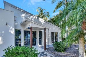 une maison blanche avec des palmiers devant elle dans l'établissement Lake Palm Resort Luxury Retreat absolute Waterfront on 3 acres at Lake Macquarie., à Dora Creek