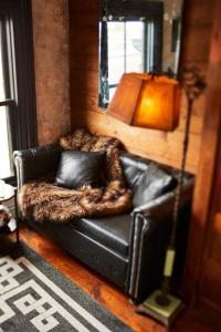 a black leather couch with a faux fur blanket at Crew's Quarters Boarding House - Caters to Men in Provincetown