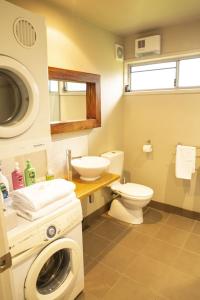 a bathroom with a washing machine and a toilet at Little Norfolk Bay Events and Chalets in Taranna