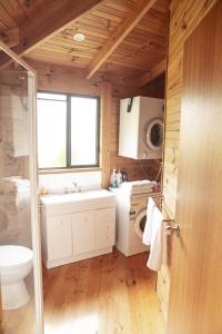 a bathroom with a sink and a washing machine at Little Norfolk Bay Events and Chalets in Taranna