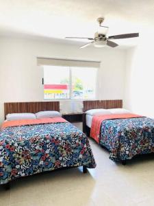 a bedroom with two beds and a ceiling fan at Departamento céntrico en Cancún in Cancún