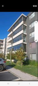 a large apartment building with a car parked in front of it at vip huertos familiares in San Pedro de la Paz