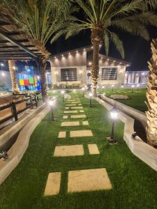 un jardin avec des palmiers et des lumières sur l'herbe dans l'établissement شاليه ومنتجع النخيل الريفي, à Taif