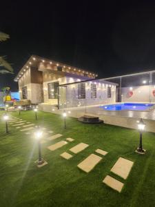 a lawn with lights in front of a building at night at شاليه ومنتجع النخيل الريفي in Taif