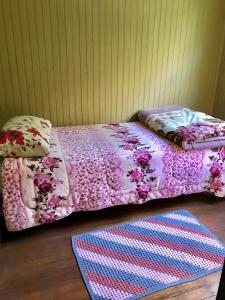 a bed with a pink comforter and a rug at Refúgio Linda Vista in Canela