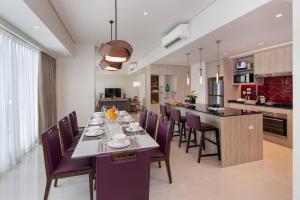 a dining room and kitchen with a long table and purple chairs at Somerset Central Salcedo Makati in Manila