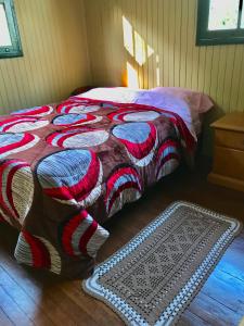 a bed with a colorful blanket and a rug in a room at Refúgio Linda Vista in Canela