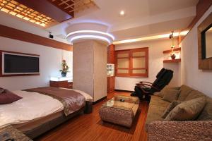 1 dormitorio con cama, sofá y TV en ホテル　Kirara en Kurosu