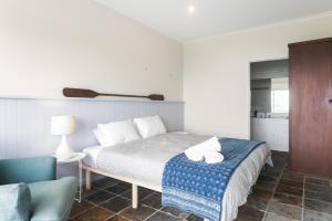 a bedroom with a bed and a blue chair at The Glass House Mollymook Beach in Mollymook +2 photos