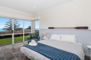 a bedroom with a bed and a large window at The Glass House Mollymook Beach in Mollymook