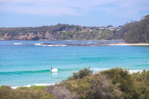 a person riding a wave on a surfboard in the ocean at The Glass House Mollymook Beach in Mollymook