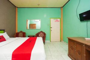 a bedroom with a bed with a red and white blanket at Reddoorz Syariah At Hotel Matahari 2 in Jambi