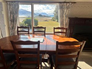 einen Esstisch mit Stühlen und ein großes Fenster in der Unterkunft Garden Cottage - Lake Tekapo in Lake Tekapo