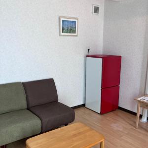 uma sala de estar com um sofá e um frigorífico em Kakunodate Guest House Choux em Senboku