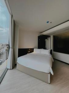a bedroom with a white bed and a large window at The Concept Hotel HCMC- District 1 in Ho Chi Minh City
