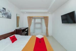 a bedroom with a bed and a desk and a television at RedDoorz Syariah At Wisma Djokorio Poncokusumo in Gubukklakah