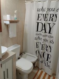 a bathroom with a toilet and a shower curtain at Atenea in Chivilcoy