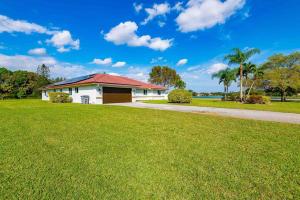 une maison blanche avec un toit rouge sur une pelouse dans l'établissement 4/3.5 House with pool- Boynton Beach, FL., à Boynton Beach