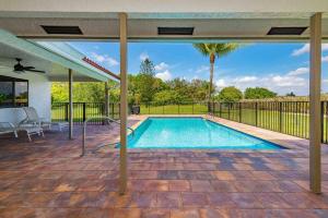 a swimming pool on a patio with an umbrella at 4/3.5 House with pool- Boynton Beach, FL. in Boynton Beach