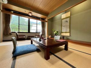 a living room with a wooden table and a chair at Gokayama Onsen Akaokan in Nanto +71 photos