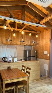 a kitchen with a wooden table and chairs and lights at Taeheung Art Theater Pension in Seogwipo