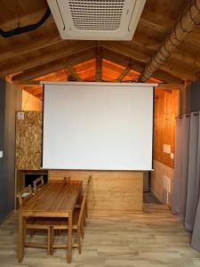 a large screen in a room with a wooden table at Taeheung Art Theater Pension in Seogwipo