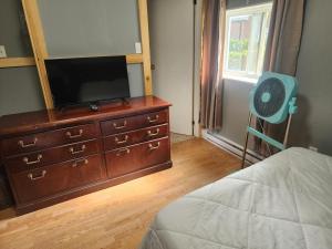 a bedroom with a dresser with a television and a fan at Earthquest Lodge in Port Burwell