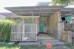ein Haus mit einem weißen Tor und einer blauen Tür in der Unterkunft OYO 92825 Kamar Lombok in Kuripan
