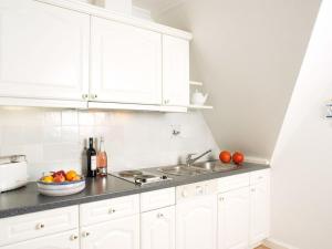 a kitchen with white cabinets and a sink and some fruit at Enenhoog-Strandlaeufer in Kampen