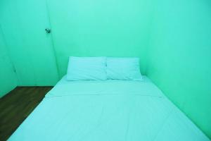 uma pequena cama num quarto com paredes azuis em SPOT ON 92843 Paris Syariah em Nagoya