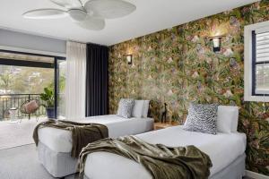 two beds in a room with floral wallpaper at Jungle Cubby - by Coast Hosting in Terrigal