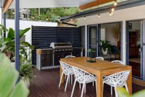 uma cozinha exterior com uma mesa de madeira e cadeiras em Jungle Cubby - by Coast Hosting em Terrigal