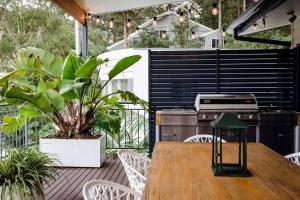 a patio with a table and a grill and plants at Jungle Cubby - by Coast Hosting in Terrigal