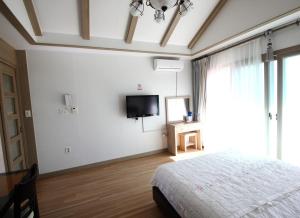 Schlafzimmer mit einem Bett und einem Flachbild-TV in der Unterkunft Jeju Soranghozen Pension in Seogwipo