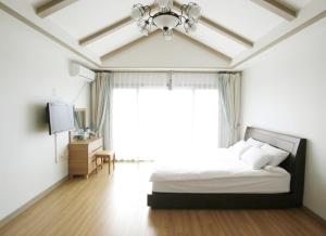 ein Schlafzimmer mit einem Bett und einem großen Fenster in der Unterkunft Jeju Soranghozen Pension in Seogwipo