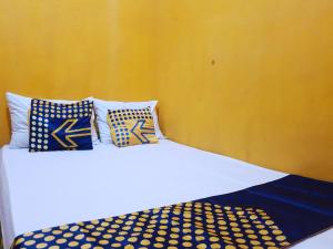 a white bed with blue and yellow pillows on it at SPOT ON 92857 Kos Haji Jakfar Syariah in Banyuwangi