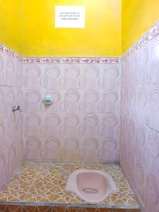 a bathroom with a pink toilet with a yellow wall at SPOT ON 92857 Kos Haji Jakfar Syariah in Banyuwangi