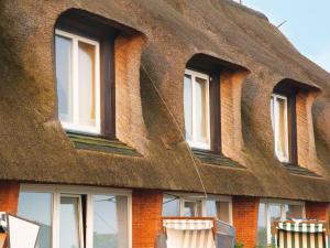a building with a thatched roof with windows at Kampbarg-36 in Kampen