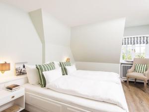 a white bedroom with a white bed and a chair at Kojenhof-2 in Kampen