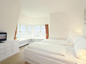 ein weißes Schlafzimmer mit einem Bett und einem TV in der Unterkunft Bröns-Fén in Kampen