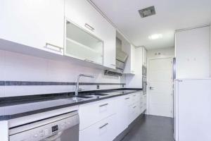 een witte keuken met een wastafel en een koelkast bij Impresionante apartamento de 4 dormitorios 3 baños y 2 plazas de garaje in Madrid