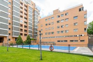 Impresionante apartamento de 4 dormitorios 3 baños y 2 plazas de garaje في مدريد: مسبح امام بعض المباني الطويلة