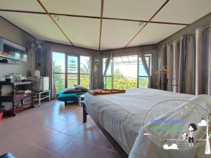 a bedroom with a large bed and a living room at Baan Suan Plearndara in Wang Nam Khieo