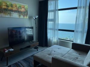 a living room with a television and a large window at Kota Kinabalu Jesselton Quay Sea View with washing machine in Kota Kinabalu